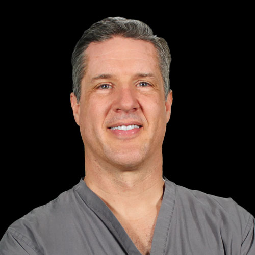 Professional headshot of ophthalmologist Dr. Aaron M. Petersen, in grey scrubs, smiling in front of a black background.