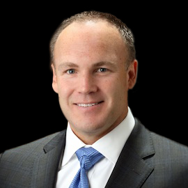 Professional headshot of optometrist Dr. Jeffrey Jackson, wearing a gray suit and patterned tie, posed in front of a black background.