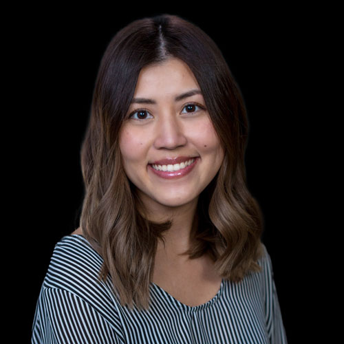 Professional headshot of Dr.Kate Trinh optometrist at Southwestern Eye Center, wearing a patterned top, smiling confidently against a dark back-lit background.