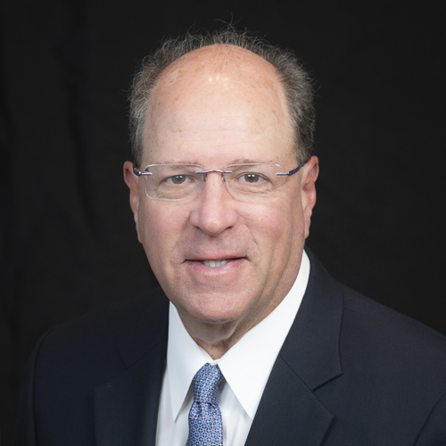 headshot of ophthalmologist Dr. Daniel Adelberg, wearing a dark suit and striped tie, posed against a neutral background.