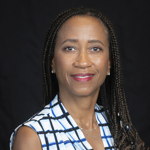 Professional headshot of ophthalmologist Dr. Renee McCoy, wearing a patterned top and earrings, smiling in front of a dark background.