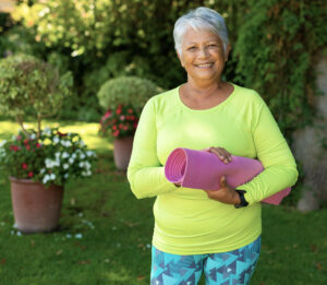 Cornea specialist in Arizona patient smiling outdoors holding a yoga mat after successful corneal treatment