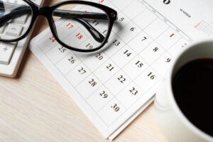Desk scene with eyeglasses resting on a paper calendar as a reminder of how to prepare for your upcoming eye exam at Southwestern Eye Center