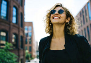After learning more about lens coatings at Southwestern Eye Center, a young millenial is happy to be outside in her UV protected sunglasses.