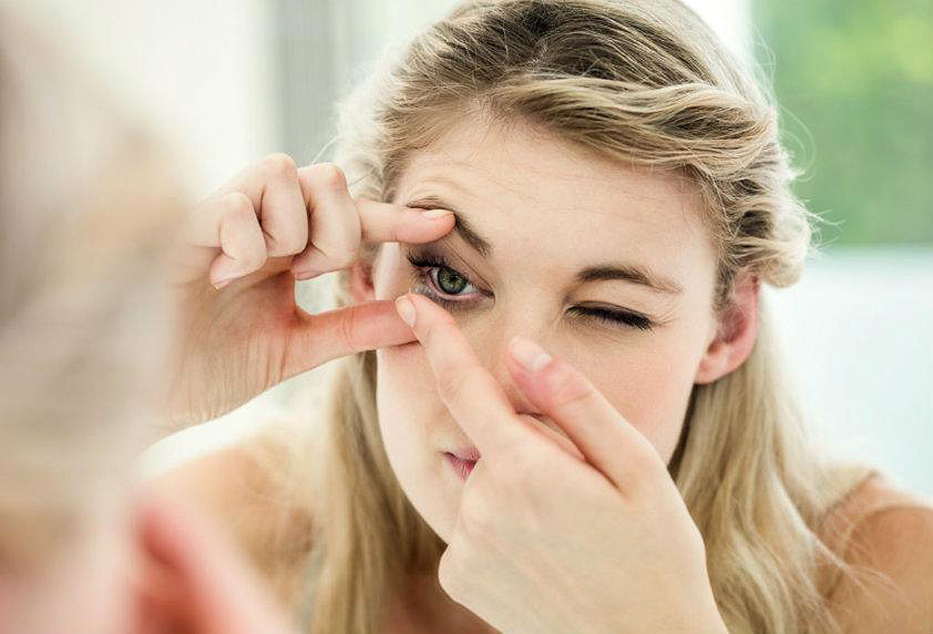 woman putting in her contact lens properly after lewarning more at Southwestern Eye Center.