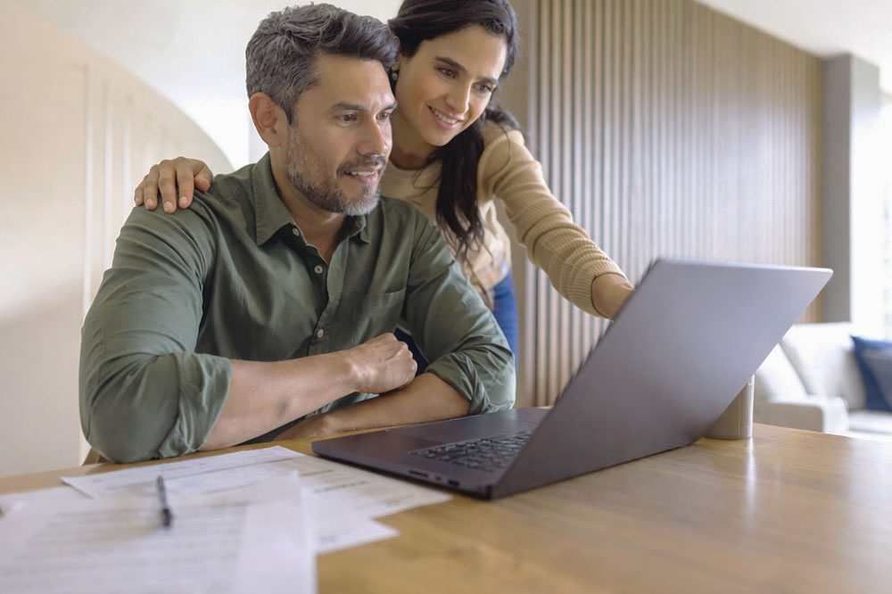 Couple reviewing finances on a laptop at home, representing Refractive Lens Exchange costs, budgeting for vision correction surgery and long-term eye care decisions.