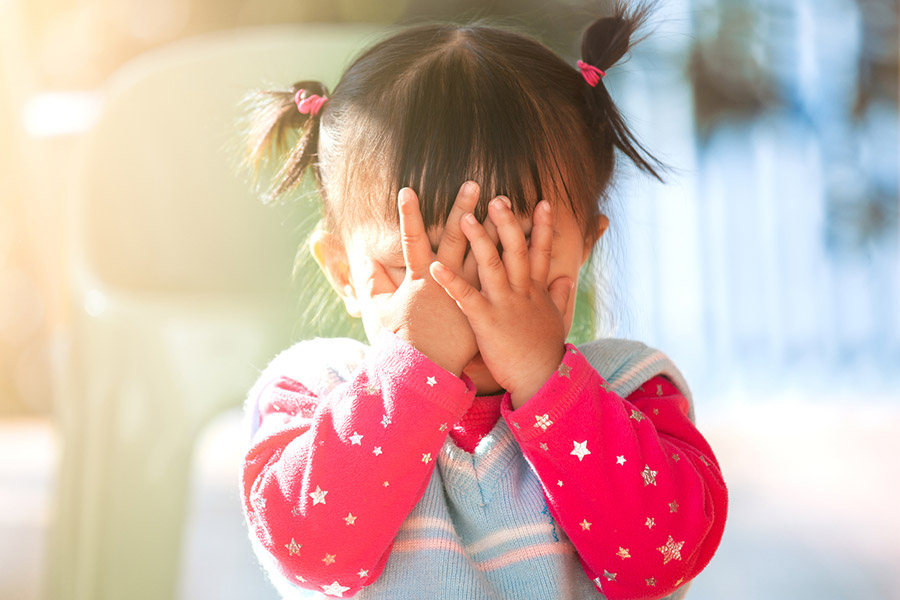 Child covering their eyes with hands while crying, illustrating emotional tears and the science behind why we cry.