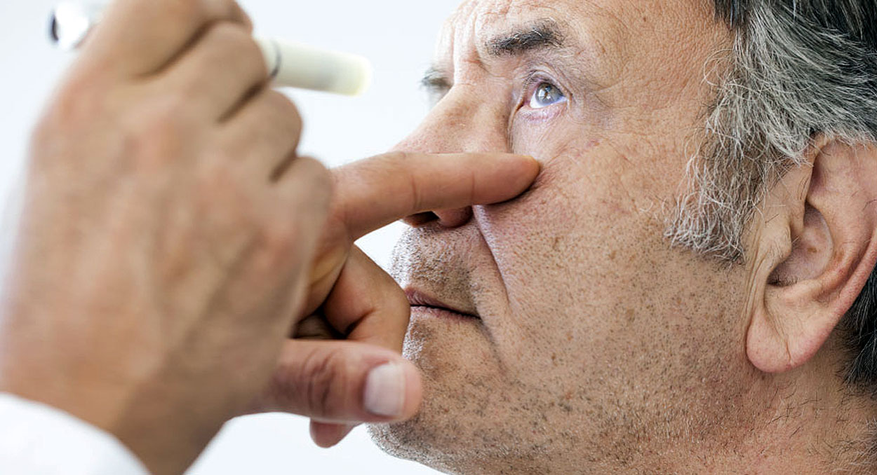 Senior man going through an eye exam to determine if he has a detached retina at Southwestern Eye Center.