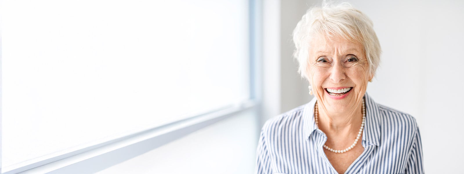 Senior lady posing at home close to a window after dry eye treatment.