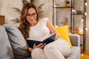 Millennial woman comfortably reading on her couch again after treating her presbyopia by using readers. Southwestern Eye Center